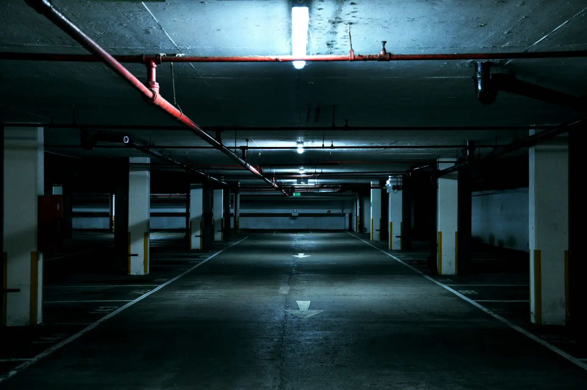 An empty underground parking garage lit by cool industrial light